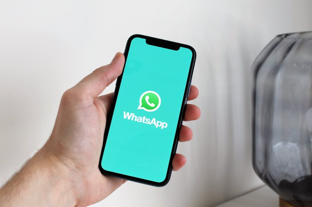 Close-up of a hand holding a smartphone displaying the WhatsApp app screen.